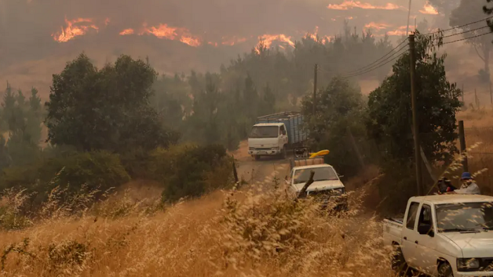 Vecinos evacúan, el 9 de febrero de 2023, por un incendio forestal en sector Rinconada de la comuna de Quillón, región de Ñuble (Chile). EFE/Esteban Paredes Drake